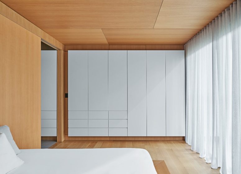 The master bedroom is super minimal and sleek there's a bed and a large storage unit plus lots of light colored wood The master bedroom is super minimal and sleek - there's a bed and a large storage unit plus lots of light colored wood