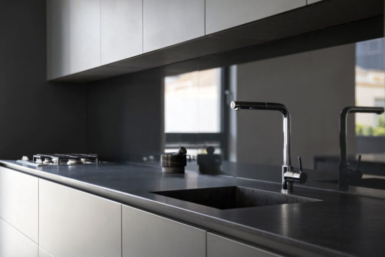 Sleek stone countertops complete the laconic and stylish look of the kitchen