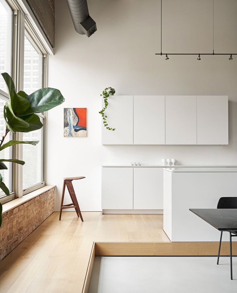 The kitchen is done with sleek white cabinets, pipes and brick elements that are extended to the living room The kitchen is done with sleek white cabinets, pipes and brick elements that are extended to the living room