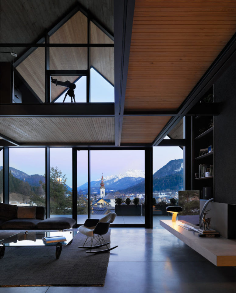 The living room is done with darker shades, with a floating console, a glass table and upholstered furniture The living room is done with darker shades, with a floating console, a glass table and upholstered furniture