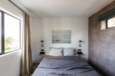 06 The bedroom is small yet peaceful, with a concrete wall, stylish bedding and an artwork
