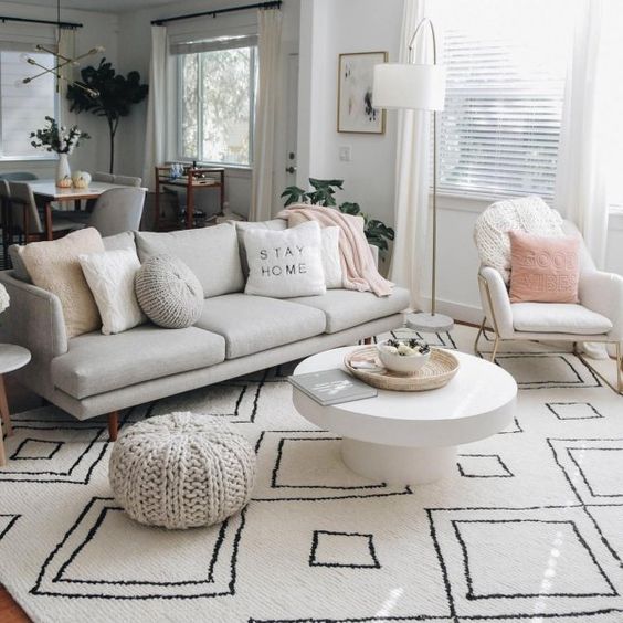 a bright living room with a white sofa and pillows is not only a centerpiece but also a divider between the living room and the kitchen