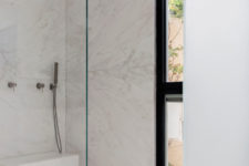 09 The bathroom is minimalist, done in white marble, with a seamless shower and a floor to ceiling window for a view and much light