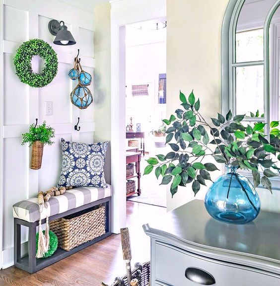 a bright farmhouse entryway with a greenery wreath and arrangements, a basket, floats and baskets
