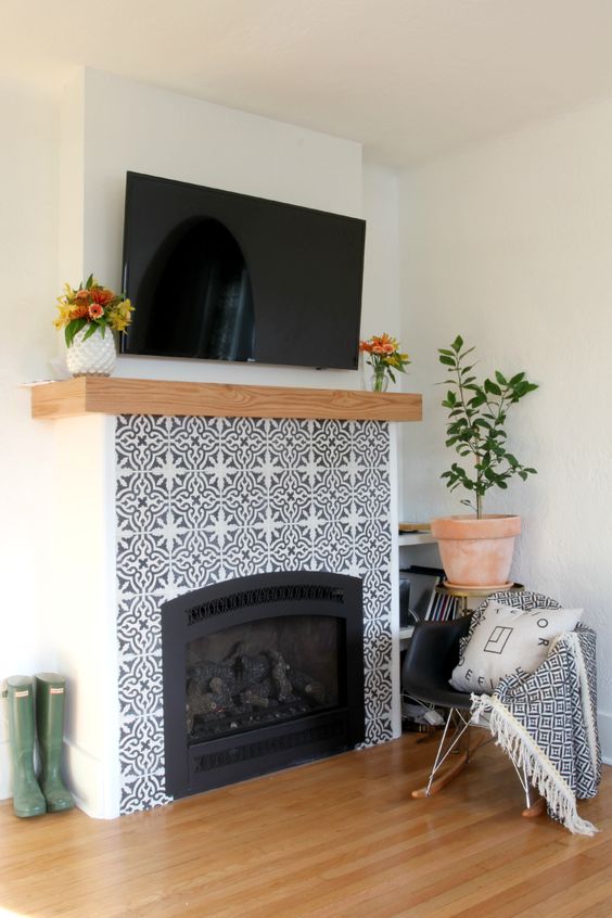 mosaic patterned grey and white tiles plus a wooden mantel look amazing and bring elegance to the rustic space