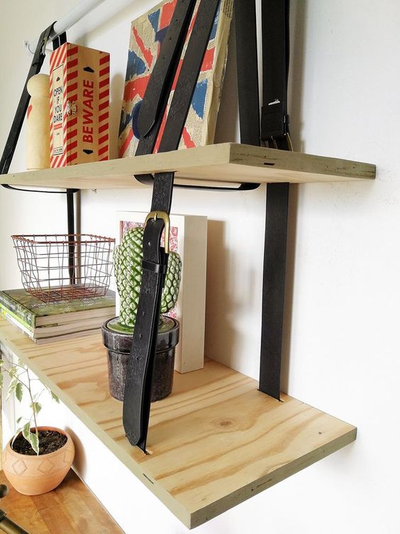 a two-layered hanging shelving unit done with plywood and leather belts is a cool modern idea