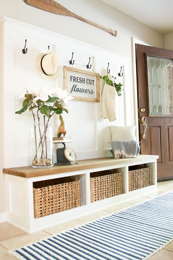 an oar, a sign, blooms and woven drawers create a light summer feel in the entryway and a striped rug helps on that
