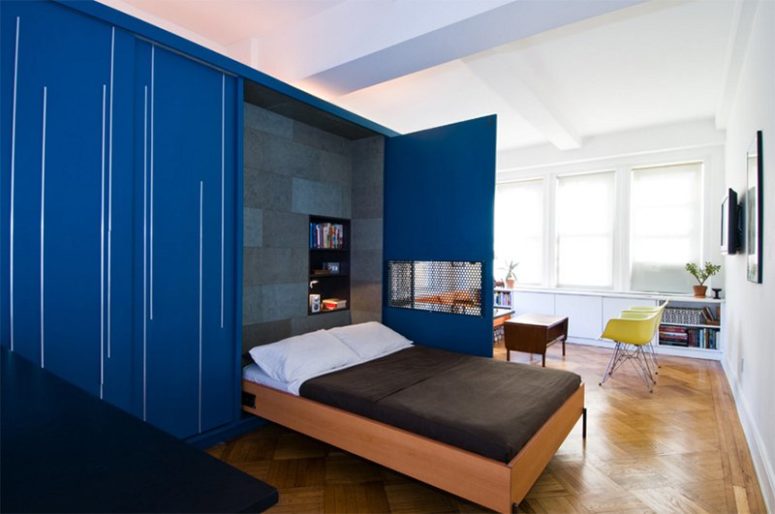 a Murphy bed integrated between the living room and the kitchen behind the bold blue doors