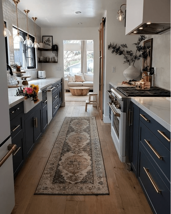 a black galley kitchen with white countertops, a white tile backsplash and a printed boho rug plus potted plants