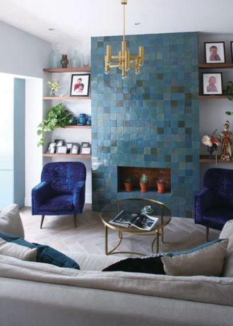 a bright living room with a faux fireplace clad with blue Zellige tiles and potted plants inside, which is a lovely statement