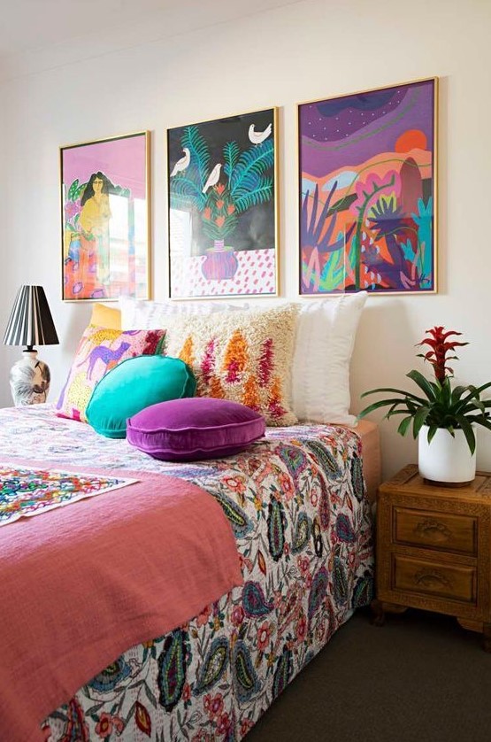 a bright maximalist bedroom with wooden furniture, a colorful gallery wall and bright textiles and bedding is amazing