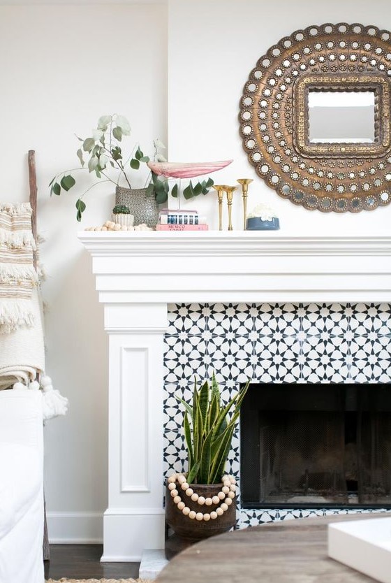 a built-in fireplace clad with black and white graphic tiles and with a refined white mantel and frame around it