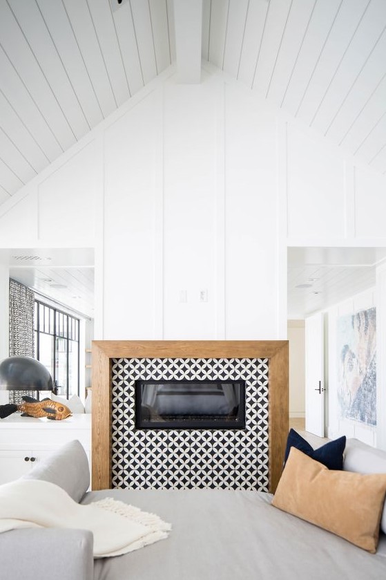 a built-in fireplace clad with black and white graphic tiles around and with a wooden frame for a contemporary space