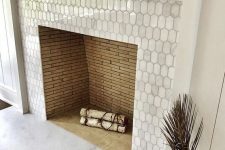 a built-in non-working fireplace clad with metal elongated hex tiles and with a white wooden frame