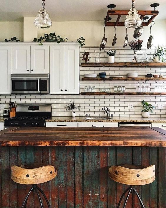 a chic vintage meets boho kitchen with a shabby chic kitchen island, white tiles, potted plants and pendant lamps