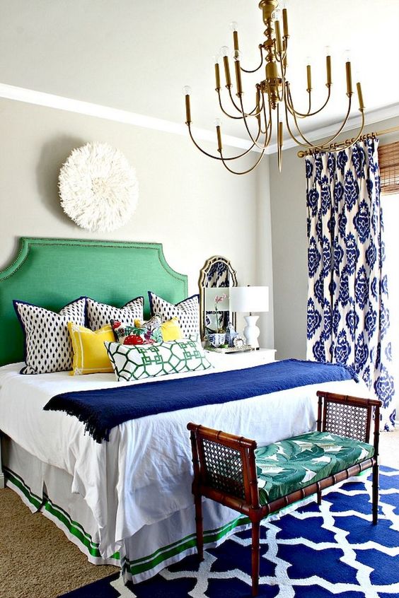 a colorful eclectic bedroom in bold blue and emerald green, with a mix of prints and vintage touches