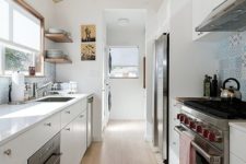 a contemporary white galley kitchen with a plywood ceiling with penddant lamps, a wooden floor and a blue tile backsplash