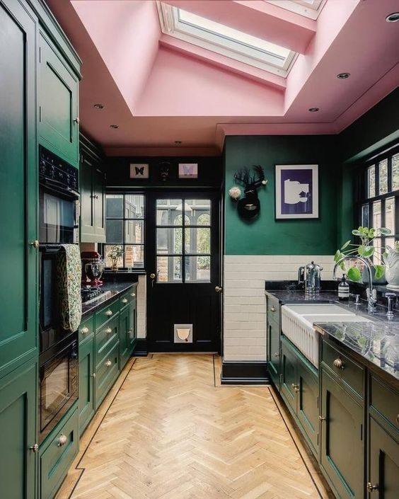 a cool kitchen with green walls and cabinetry, a pink ceiling with skylights and marble countertops is adorable