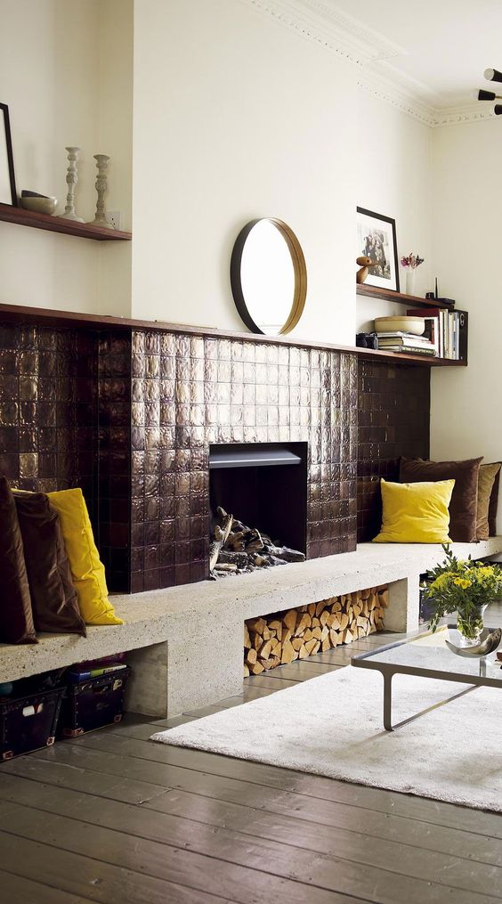 a fireplace done with metal tiles, with a firewood storage space and a concrete bench with bold pillows