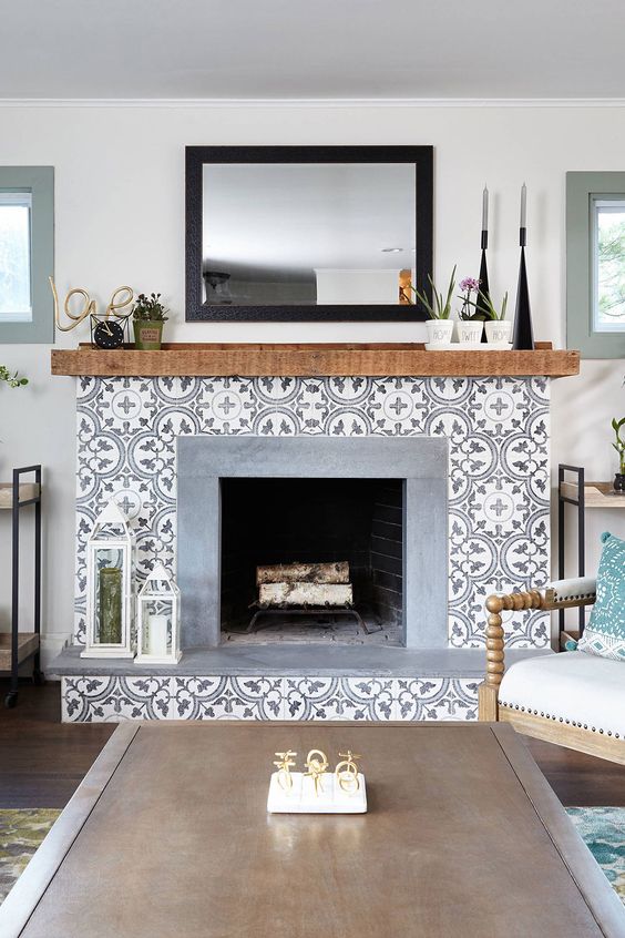 a fireplace with a beautiful printed tile surround, some decor on the mantel is a stylish idea for any modern living room