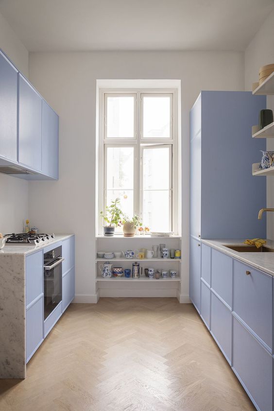 a lovely periwinkle galley kitchen with white stone countertops and open shelves plus built-in shelves for teaware