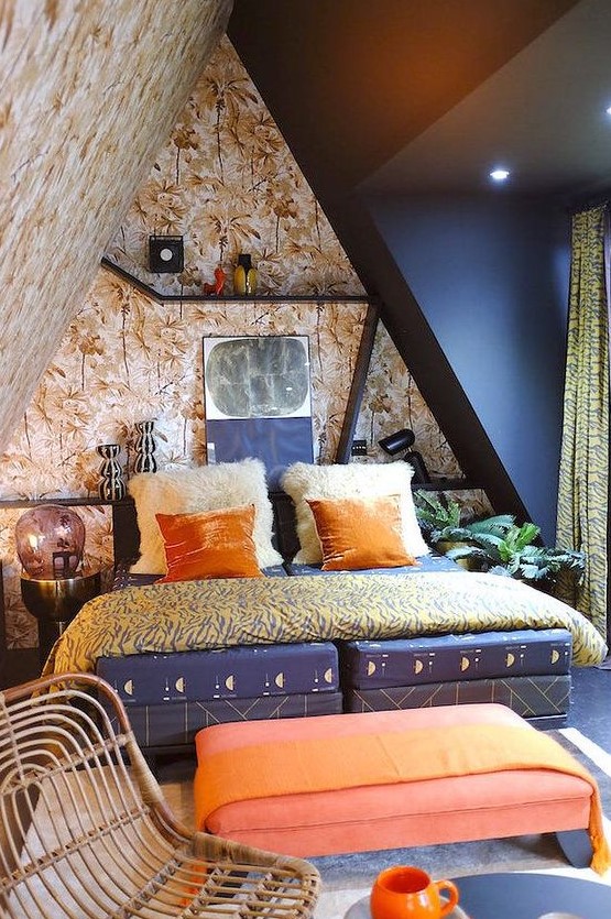 a maximalist attic bedroom with botanical walls and a black one, a navy bed, a coral ottoman, bright bedding and shelves