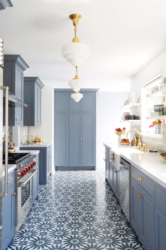 a modern farmhouse kitchen in powder blue with a mosaic tile floor, elegant pendant lamps and gilded touches for more elegance