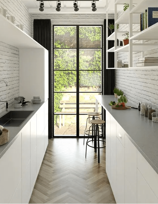 a modern white gallery kitchen with sleek cabinetry, grey stone countertops, open shelves and brick walls