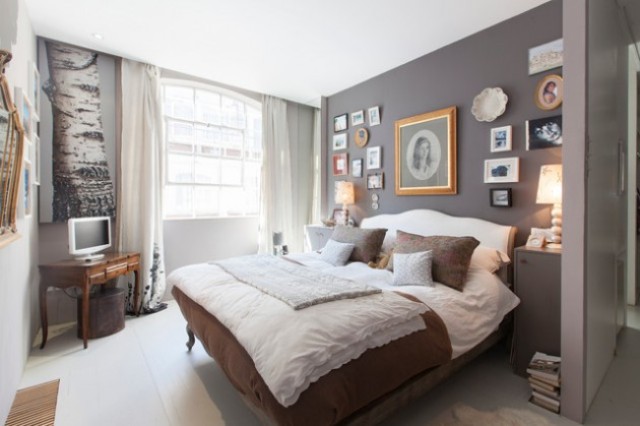 a monochrome eclectic bedroom done in grey, white and rich brown, with a vintage-inspired gallery wall, a refined bed and table and modern nightstands
