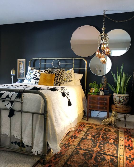 a-moody-eclectic-bedroom-with-boho-rugs-and-a-chandelier-vintage-mirrors-and-a-metal-bed-and-mid-century-modern-nightstands.jpg