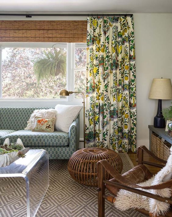 a muted color eclectic living room with printed curtains and shades, a printed blue sofa, wicker furniture and a printed rug
