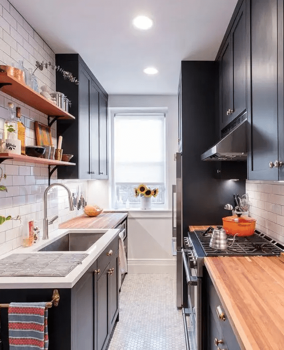a navy galley kitchen with shaker cabinets, butcherblock countertops, open shelves and some built-in lights
