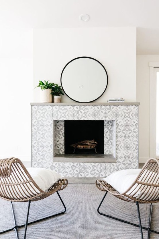 a neutral contemporary space with a fireplace clad with monochromatic patterned tiles and a laconic grey mantelw ith plants