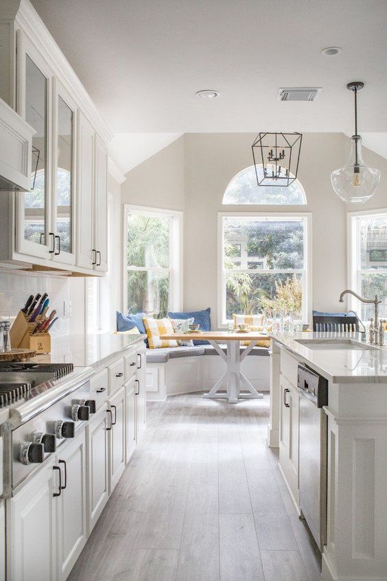 a neutral farmhouse galleykitchen with chic cabinets and white stone countertops, a wooden floor and catchy pendant lamps