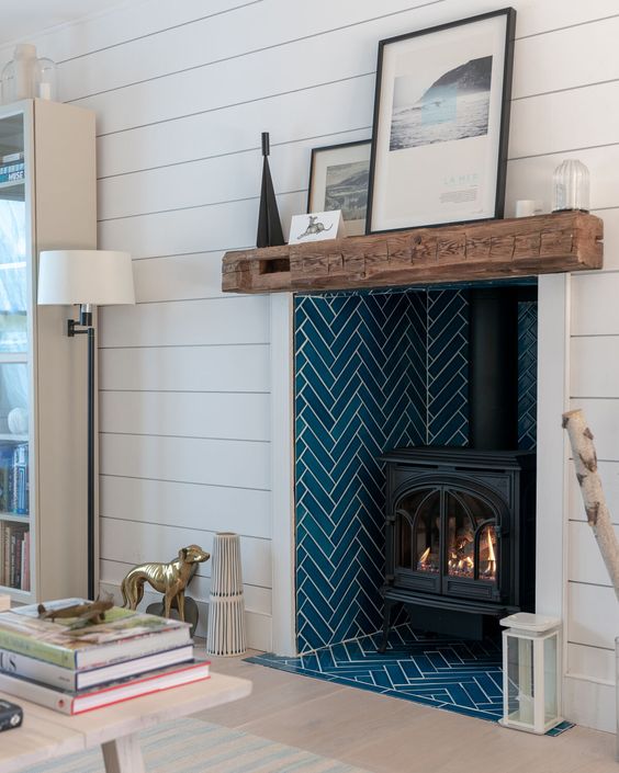 a niche clad with navy herringbone tiles and with a hearth inside is a cool and stylish solution with color and pattern