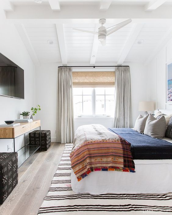 an eclectic bedroom with neutrals and various muted colors, mixed prints and mid century modern furniture