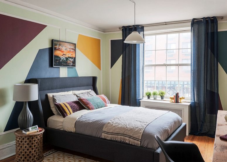 an eclectic geometric bedroom with stencils on the wlals, an upholstered black bed, carved stools and nightstands