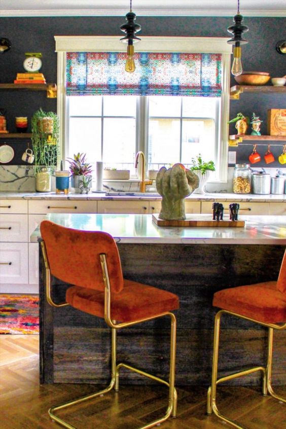 an eclectic kitchen with bold wallpaper, white cabinets, open shelves, a kitchen island, rust-colored stools and pendant lamps