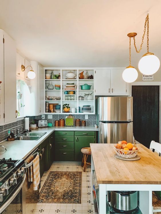 an eclectic kitchen with green and white cabinets, a printed tile backsplash and white countertops, a farmhouse kitchen island