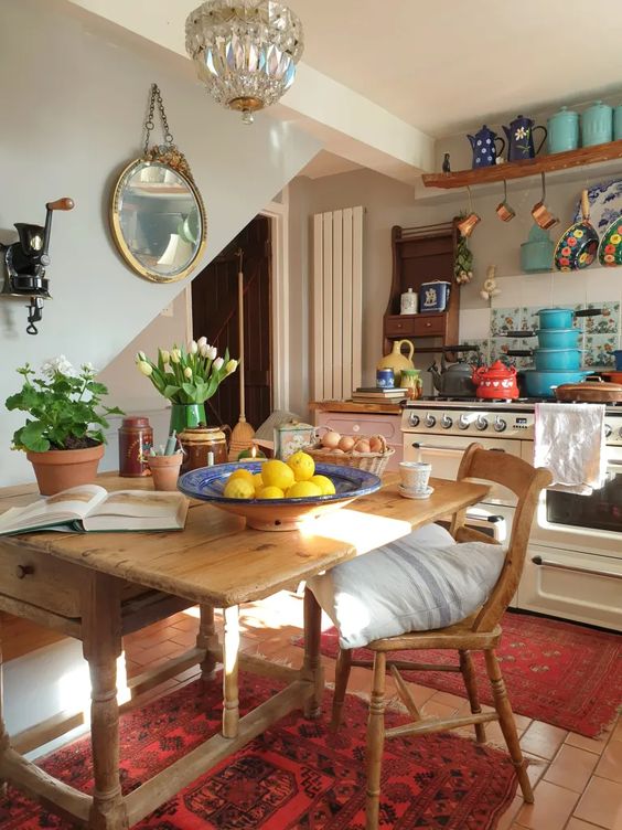 an eclectic kitchen with neutral and blush cabinets, open shelves, a vintage wooden table and a chair, a crystal pendant lamp