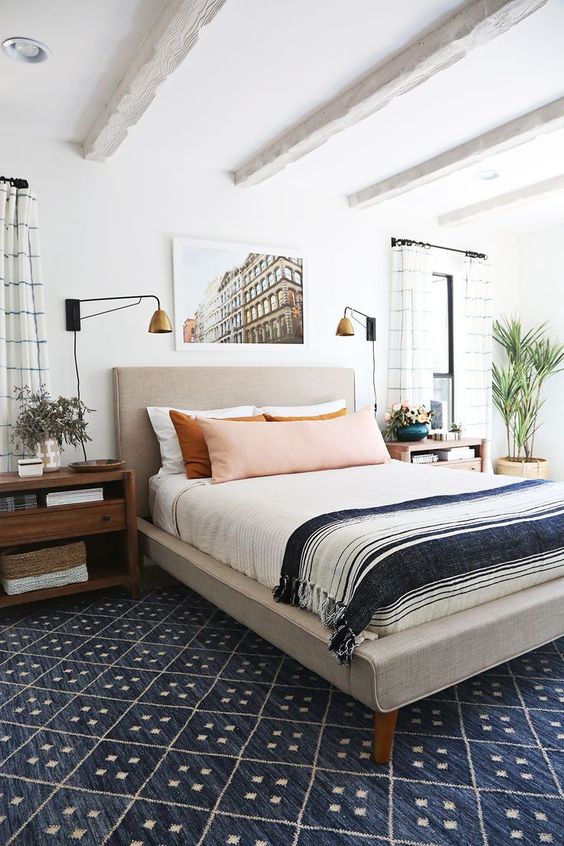 an eclectic sleeping space with an upholstered bed, wooden mid century nightstands, vintage glam lamps and much more