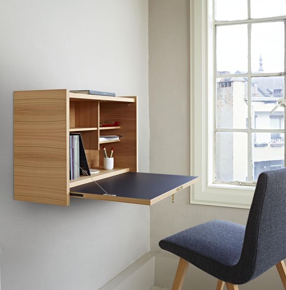 an elegant minimalist Murphy desk done in light colored plywood and navy, with stylish and neat storage compartments inside