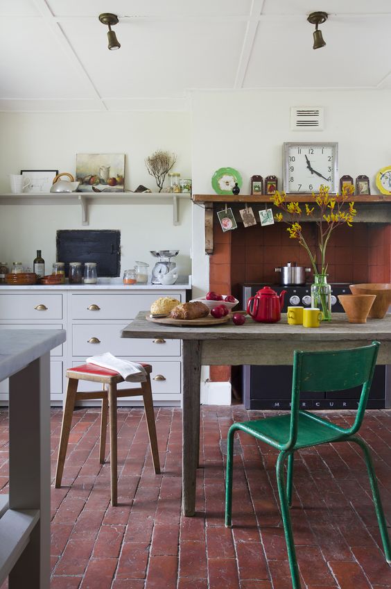 elegant white cabinets, a rustic wooden table, vintage stools and chairs in various colors and a fireplace clad with tiles