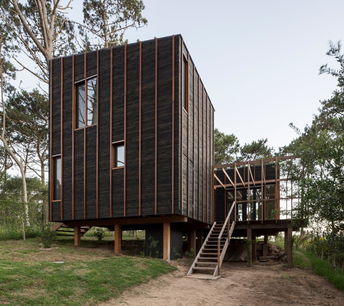 This contemporary house in Uruguay is clad with dark wood and amber stripes for a cathcy touch and features ocean views