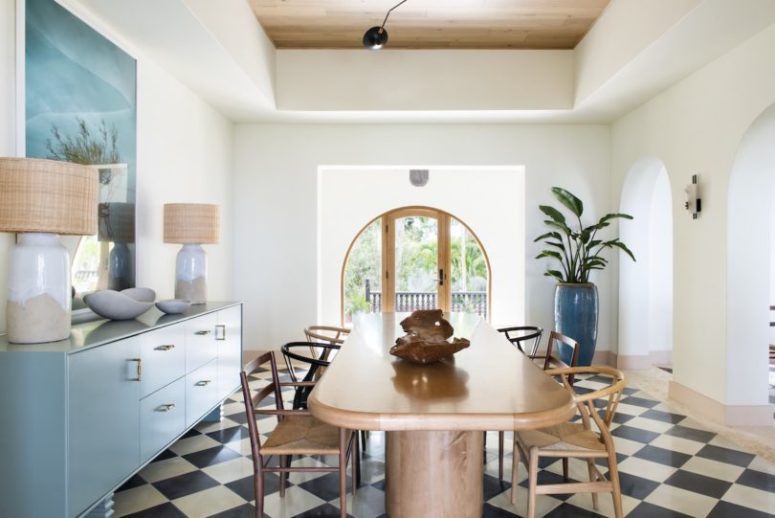 The dining room is done with a large table with curved corners and a blue sideboard plus a statement artwork The dining room is done with a large table with curved corners and a blue sideboard plus a statement artwork