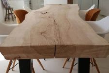 03 a light-stained dining table of a single slab with a live edge and mismatching rust and white chairs