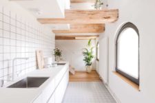 04 The kitchen is done in white, with simple tiles and sleek white cabinets plus matte countertops