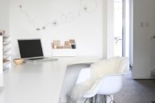 04 a minimalist white home office with a long and sleek desk, some wall-mounted cabinets and a comfy chair