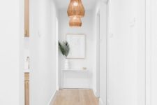 04 a white long and narrow hallway is done with wicker pendant lamps and tropical leaves to highlight the ambience