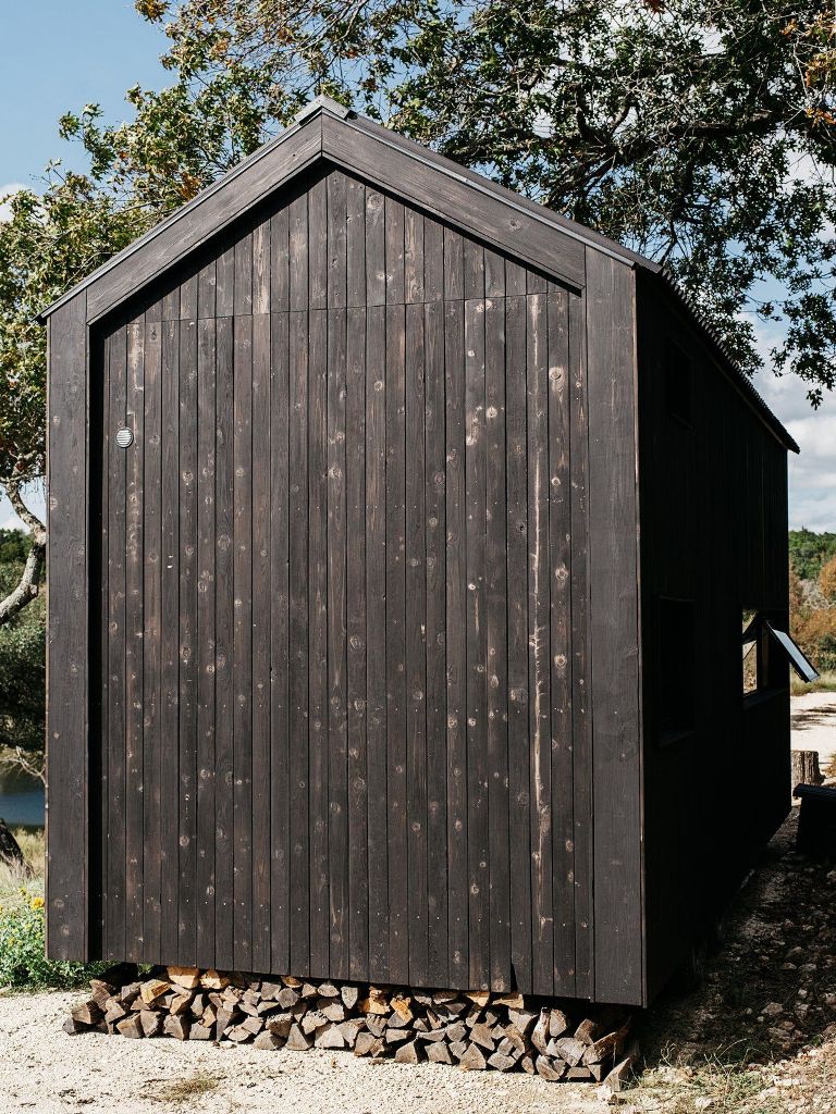 The cabin seems to be floating a few inches above the ground, allowing space for a wood-storage niche underneath